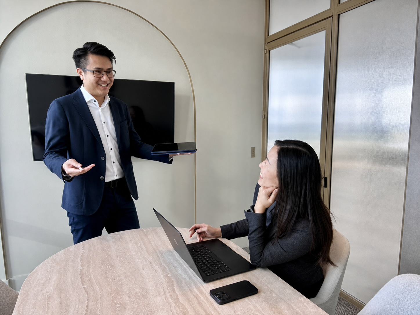 Suti walking a seated colleague through a pipeline view on a tablet in an office.